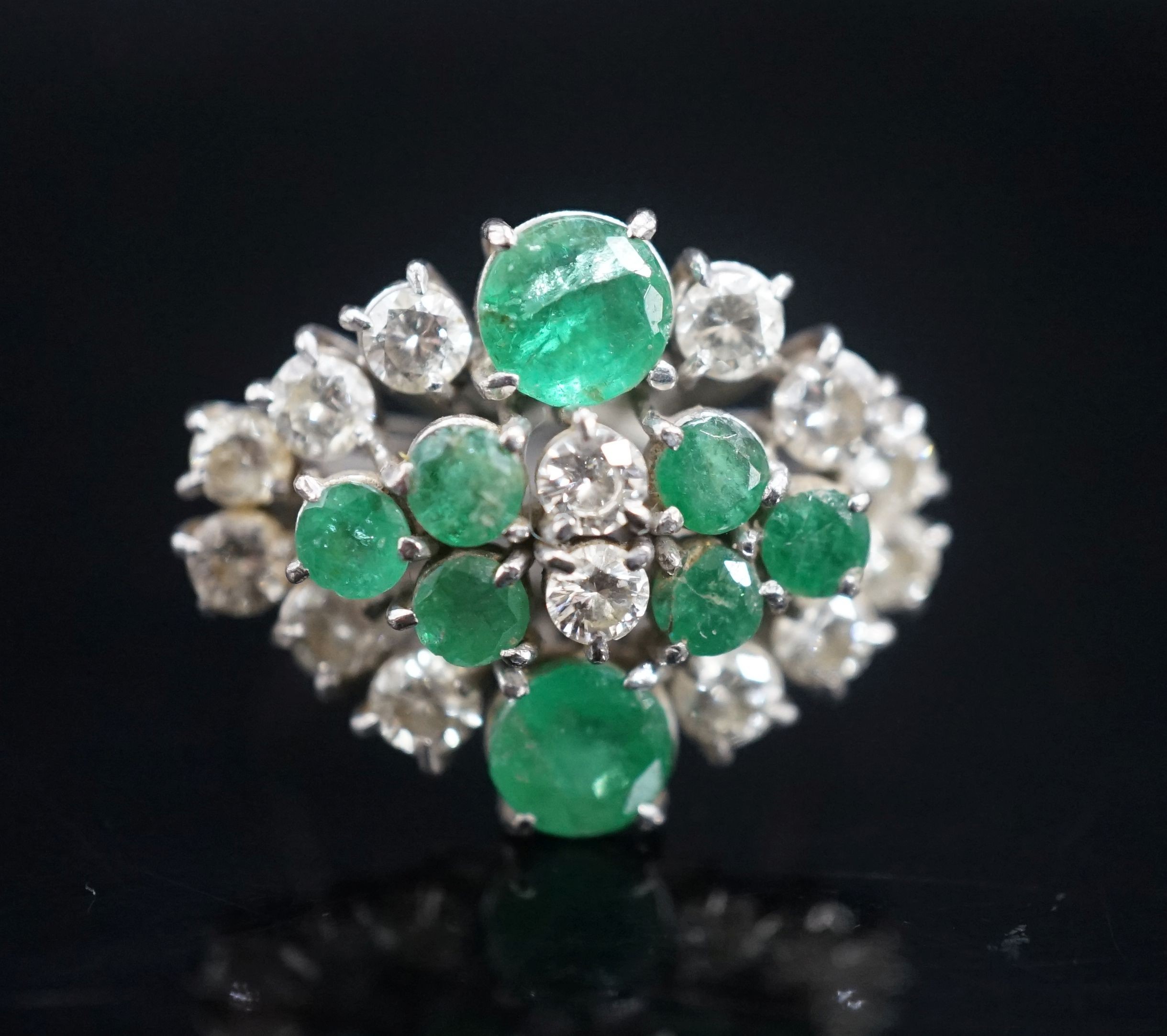 A 20th century 18ct white metal, emerald and diamond set cluster dress ring, size O/P, gross weight 7.3 grams.
